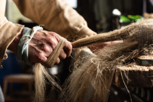 Hands heckling flax at Mallon Farm